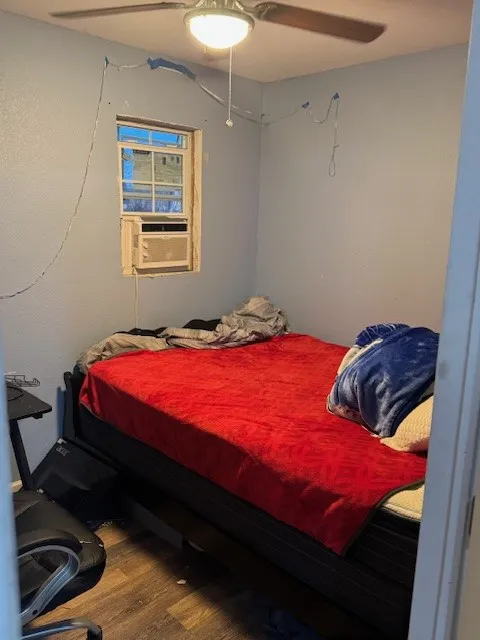 Bedroom with a ceiling fan, wood finished floors, and cooling unit