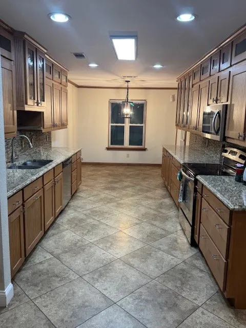 Kitchen with glass insert cabinets, backsplash, appliances with stainless steel finishes, dark stone counters, and recessed lighting