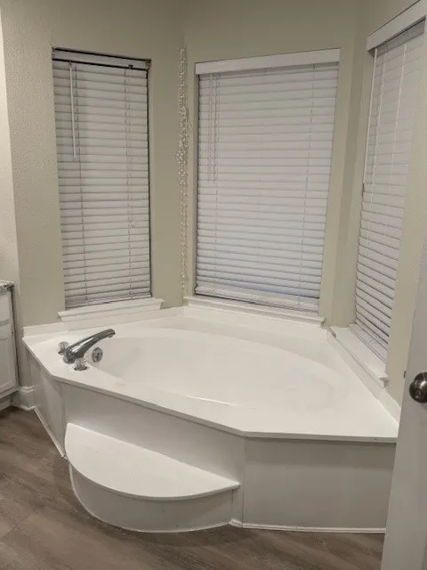 Bathroom with a bath and dark wood-type flooring