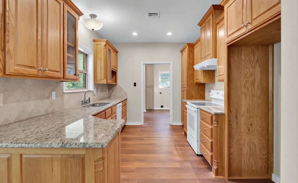 Kitchen with backsplash, white range with electric cooktop, light stone counters, light wood-type flooring, and recessed lighting
