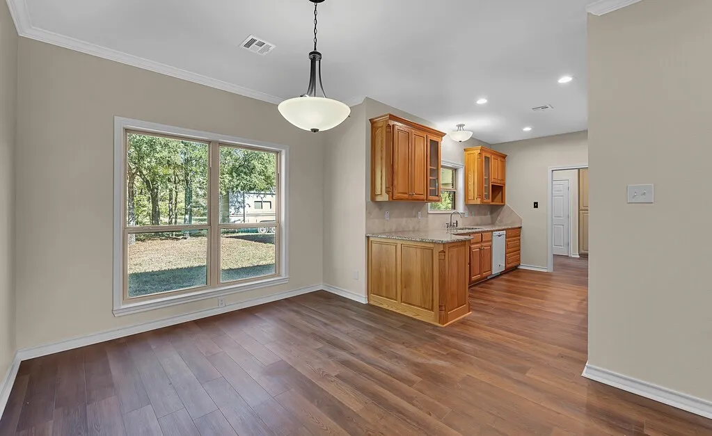Kitchen with light stone counters, brown cabinets, decorative backsplash, dark wood-style floors, and recessed lighting