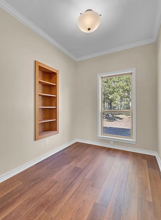 Spare room featuring ornamental molding, wood finished floors, and built in shelves