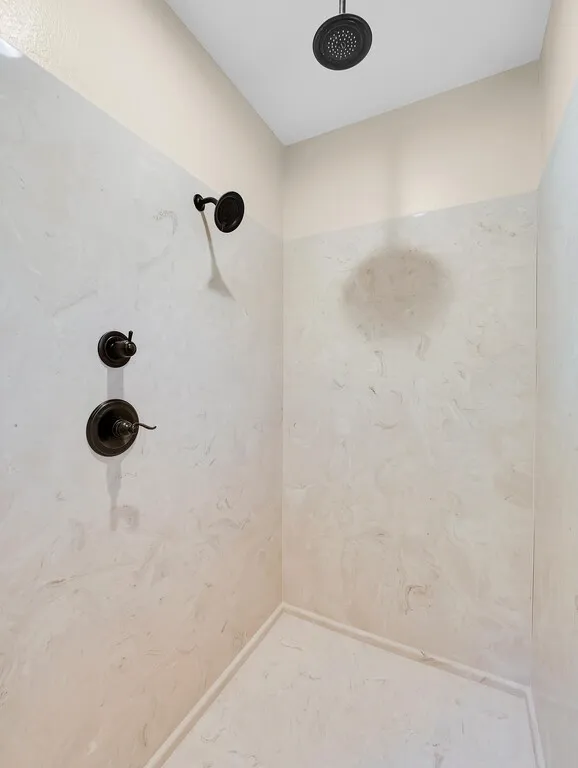 Full bath with a marble finish shower