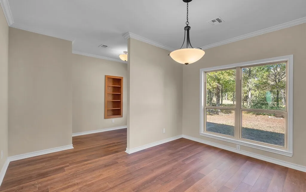 Unfurnished dining area featuring ornamental molding and dark wood finished floors