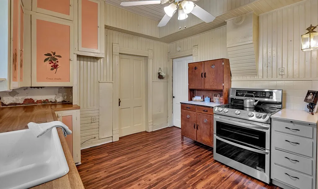 Kitchen with range with two ovens, dark wood finished floors, ceiling fan, and brown cabinetry