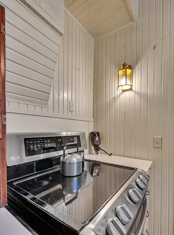 Kitchen with stainless steel range with electric cooktop, wood walls, and wood ceiling