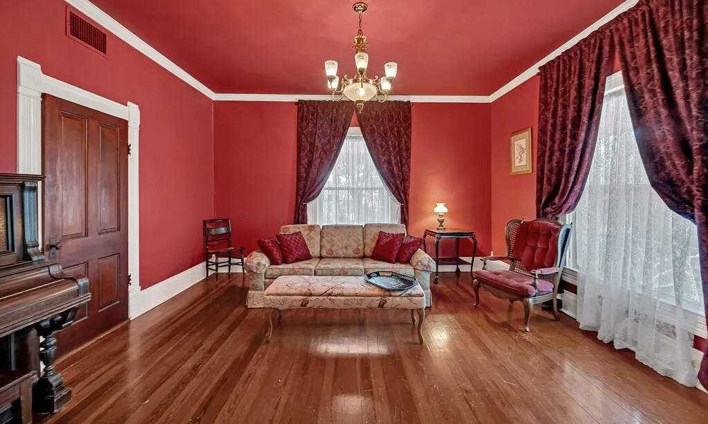 Living area with ornamental molding, wood-type flooring, and a chandelier