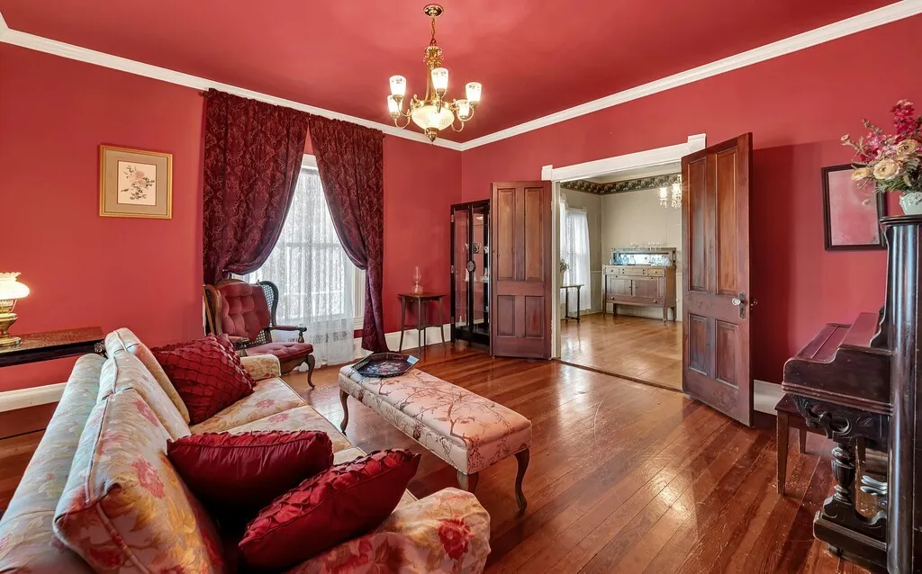 Living area featuring dark wood-type flooring, a chandelier, and crown molding