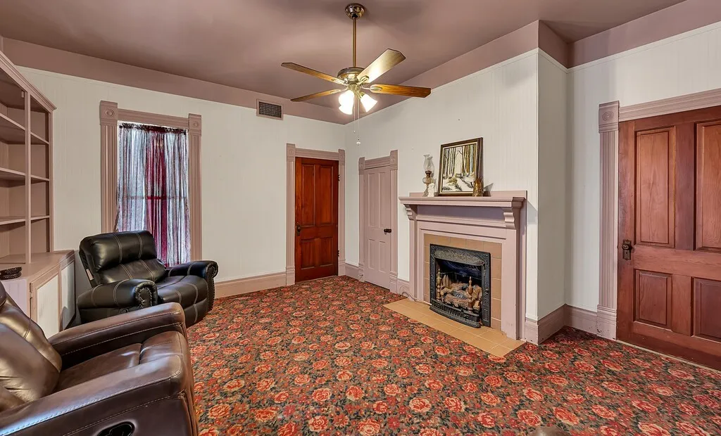 Living room featuring a fireplace, light colored carpet, and a ceiling fan