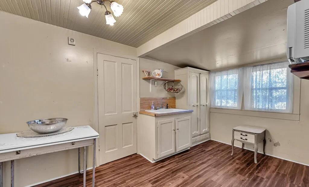 Kitchen with white cabinets, dark wood-style floors, open shelves, and light countertops