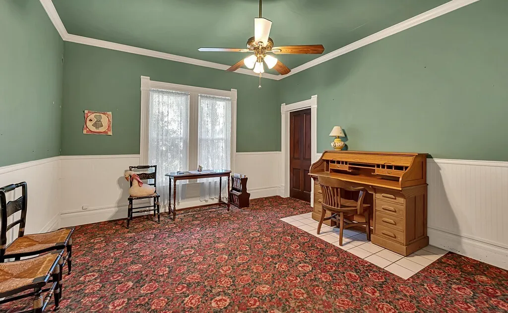 Office with a wainscoted wall, ornamental molding, a ceiling fan, and light colored carpet