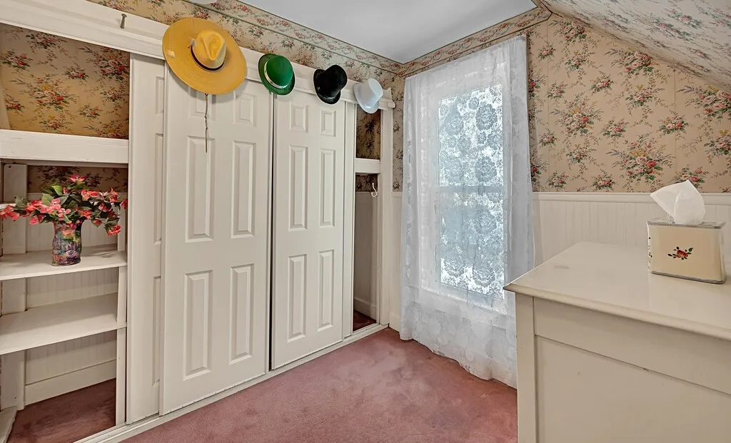 Doorway featuring carpet floors, wallpapered walls, and wainscoting