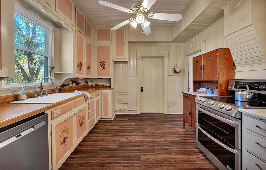 Kitchen featuring stainless steel appliances, light countertops, dark wood-style floors, and ceiling fan