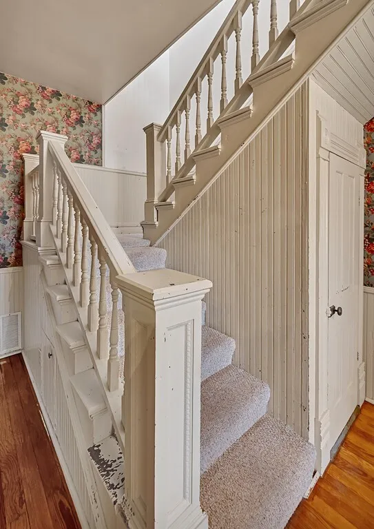 Stairs with a wainscoted wall, wallpapered walls, and hardwood / wood-style floors