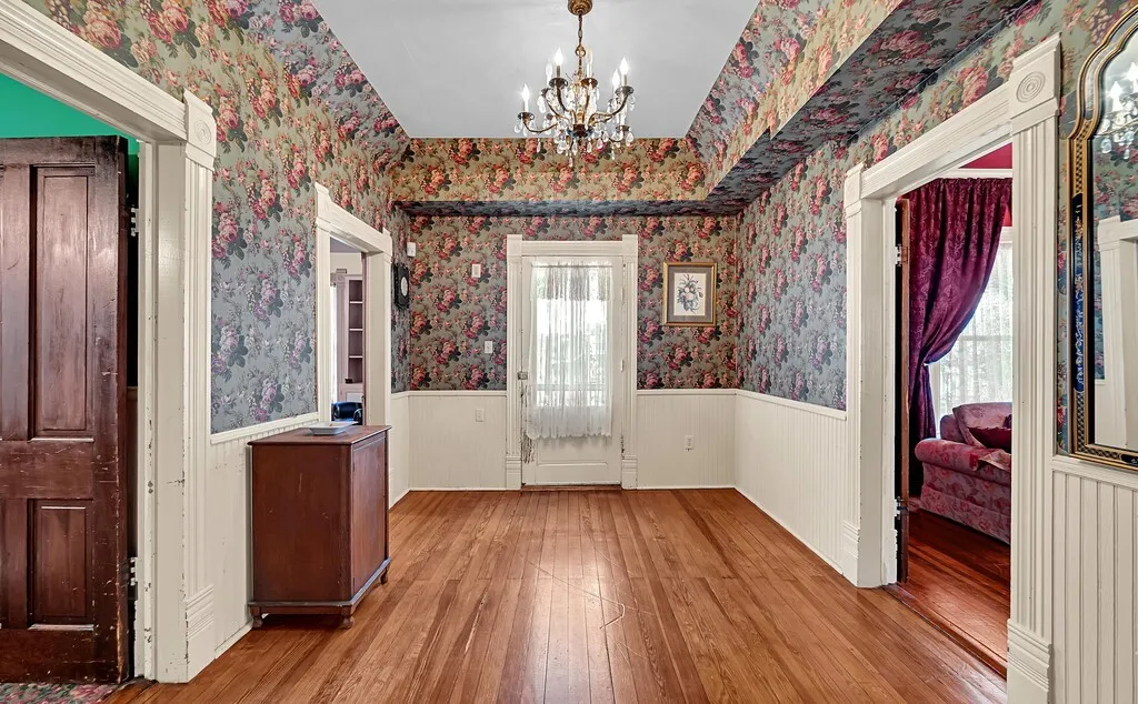 Foyer featuring a chandelier, wood-type flooring, a wainscoted wall, and wallpapered walls