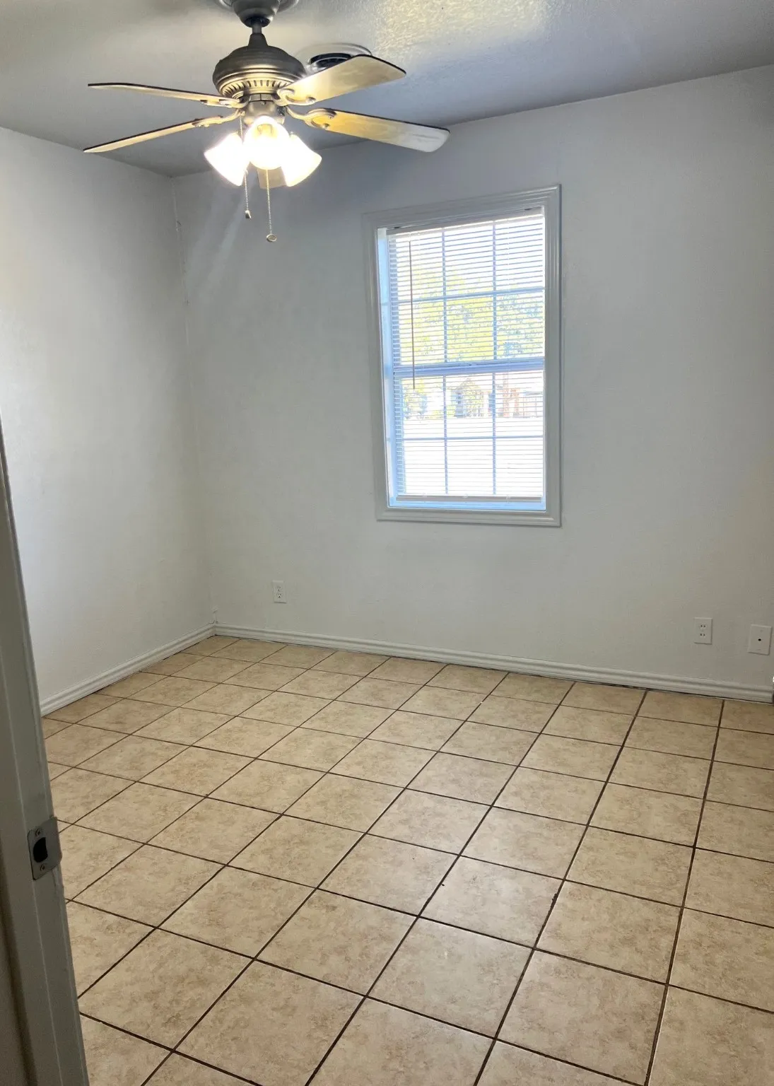 Empty room featuring light tile patterned floors, a ceiling fan, and a textured ceiling