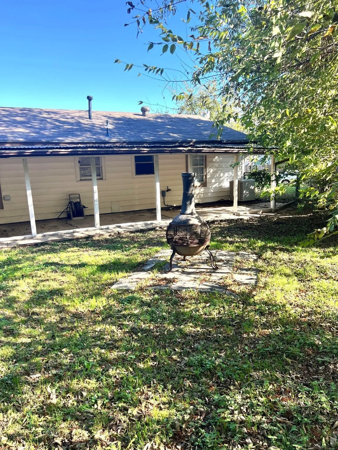 Back of house featuring an outdoor fire pit, a patio area, a lawn, and a shingled roof