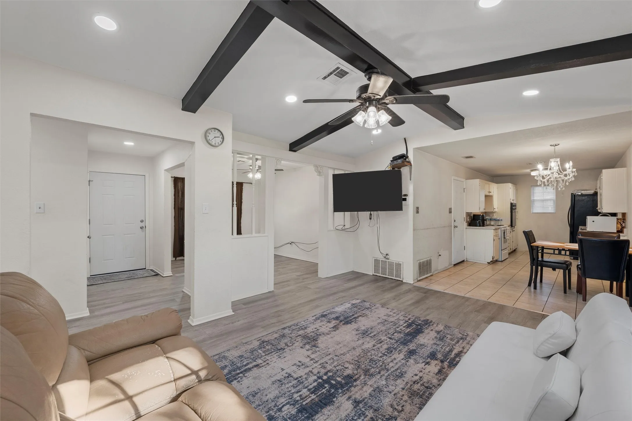 Living area featuring beam ceiling, a chandelier, light wood-style flooring, recessed lighting, and a ceiling fan