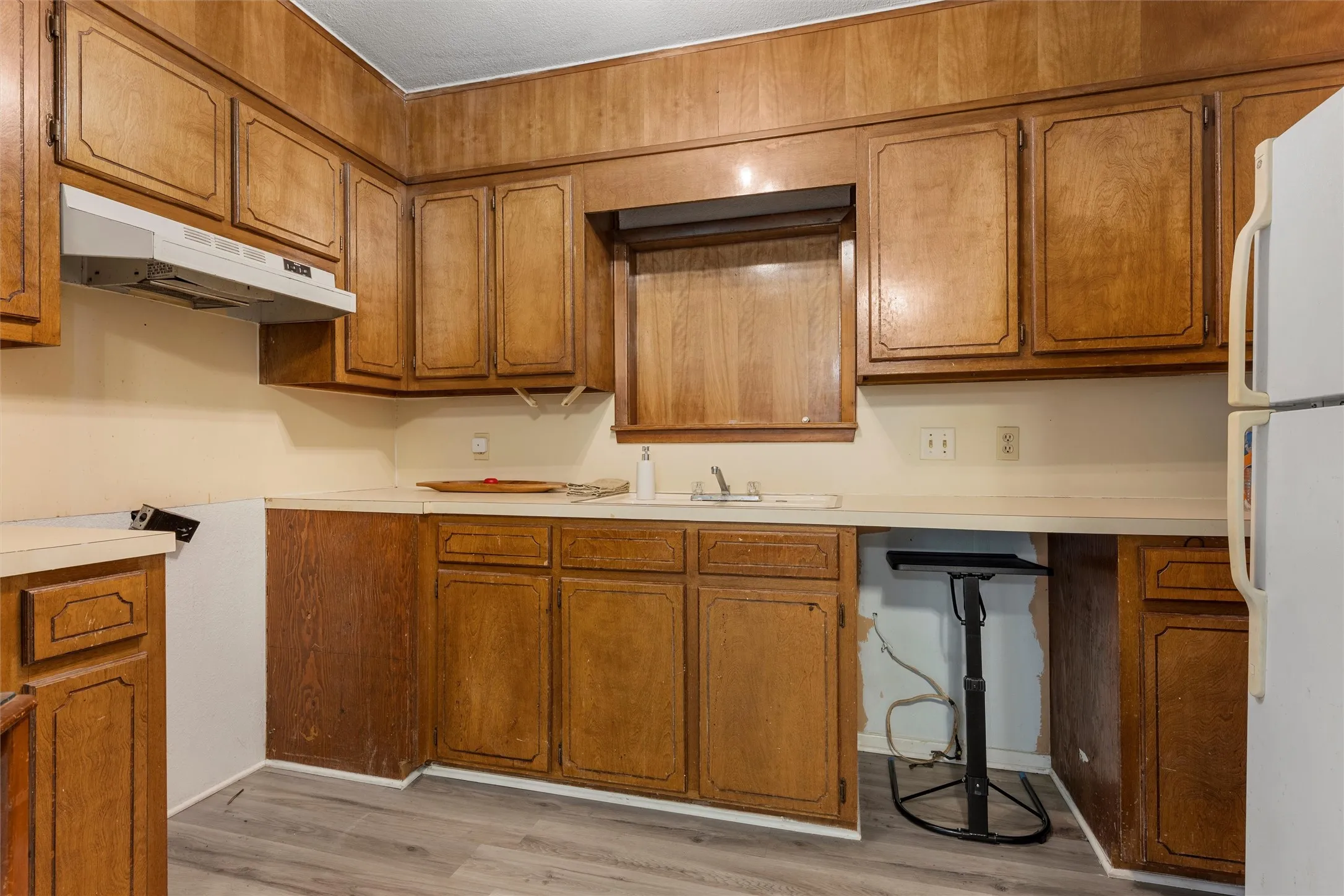 Kitchen featuring brown cabinetry, light countertops, and freestanding refrigerator