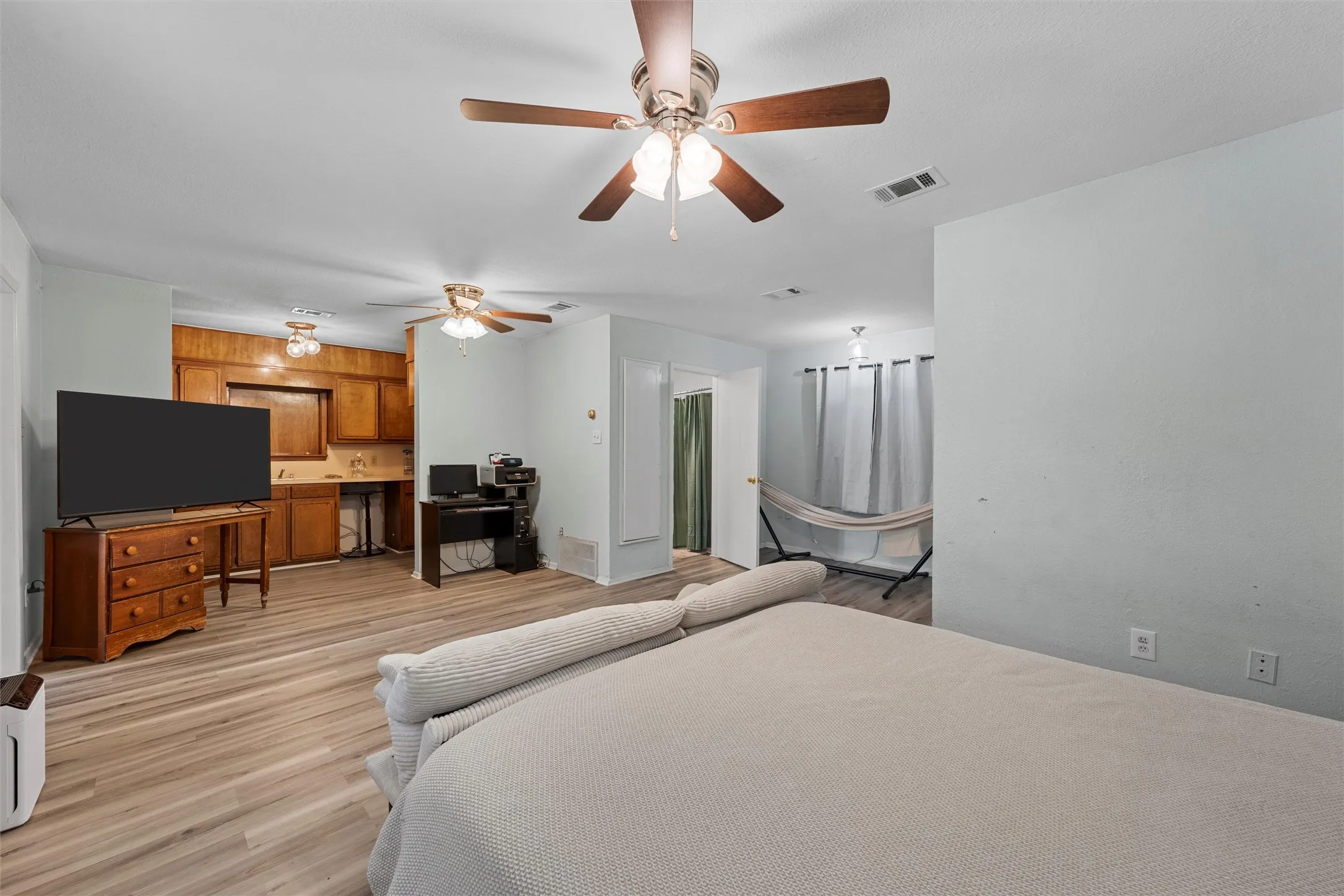Bedroom featuring light wood-style floors, a ceiling fan, and a desk