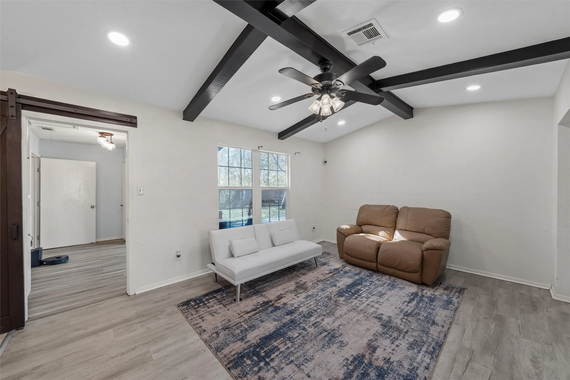 Living area with light wood-style floors, recessed lighting, a barn door, and a ceiling fan