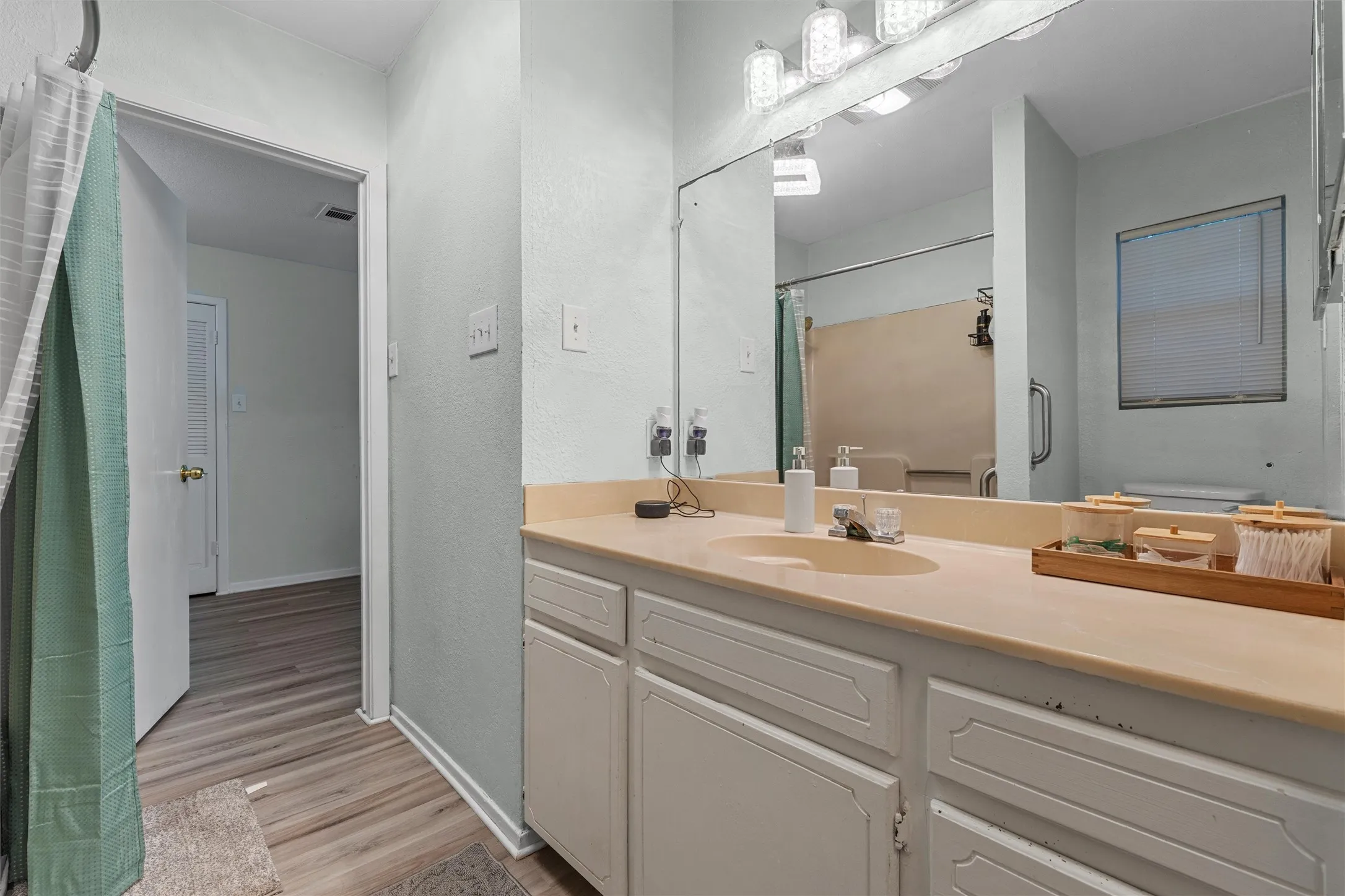 Full bathroom featuring vanity, light wood-style floors, a textured wall, and curtained shower