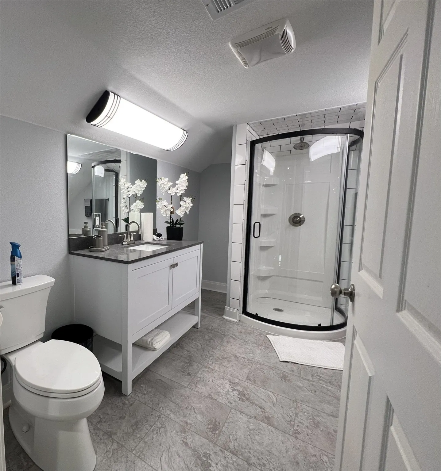 Bathroom featuring a textured ceiling, a stall shower, vanity, and lofted ceiling