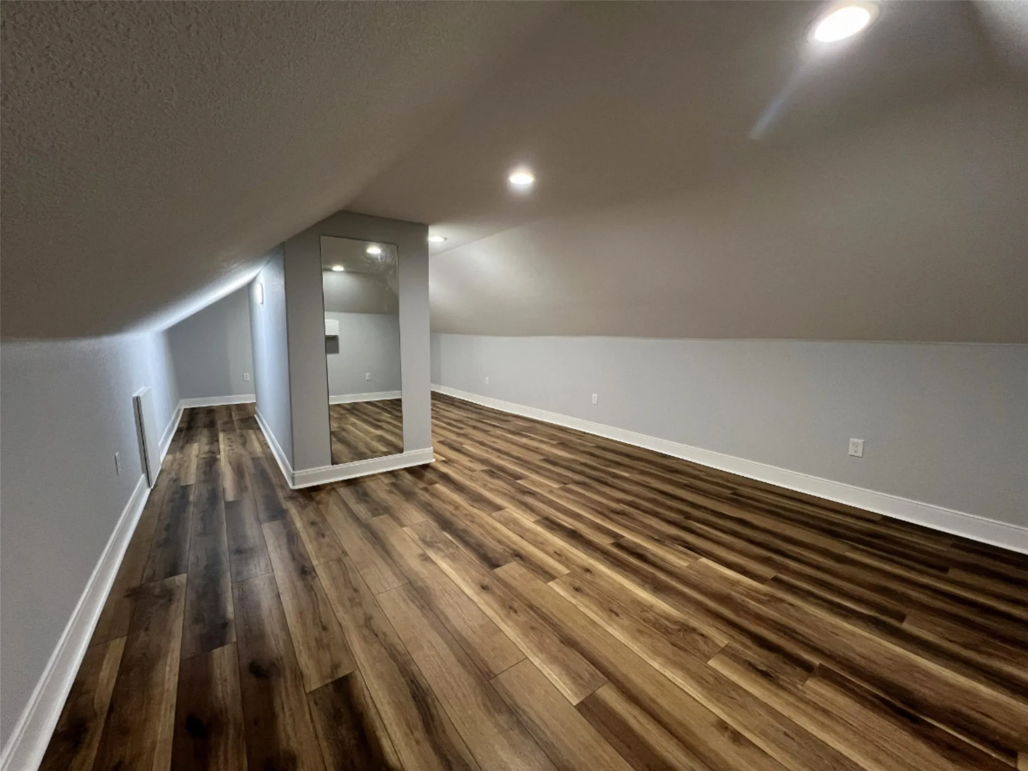 Bonus room featuring dark wood finished floors, vaulted ceiling, a textured ceiling, and recessed lighting