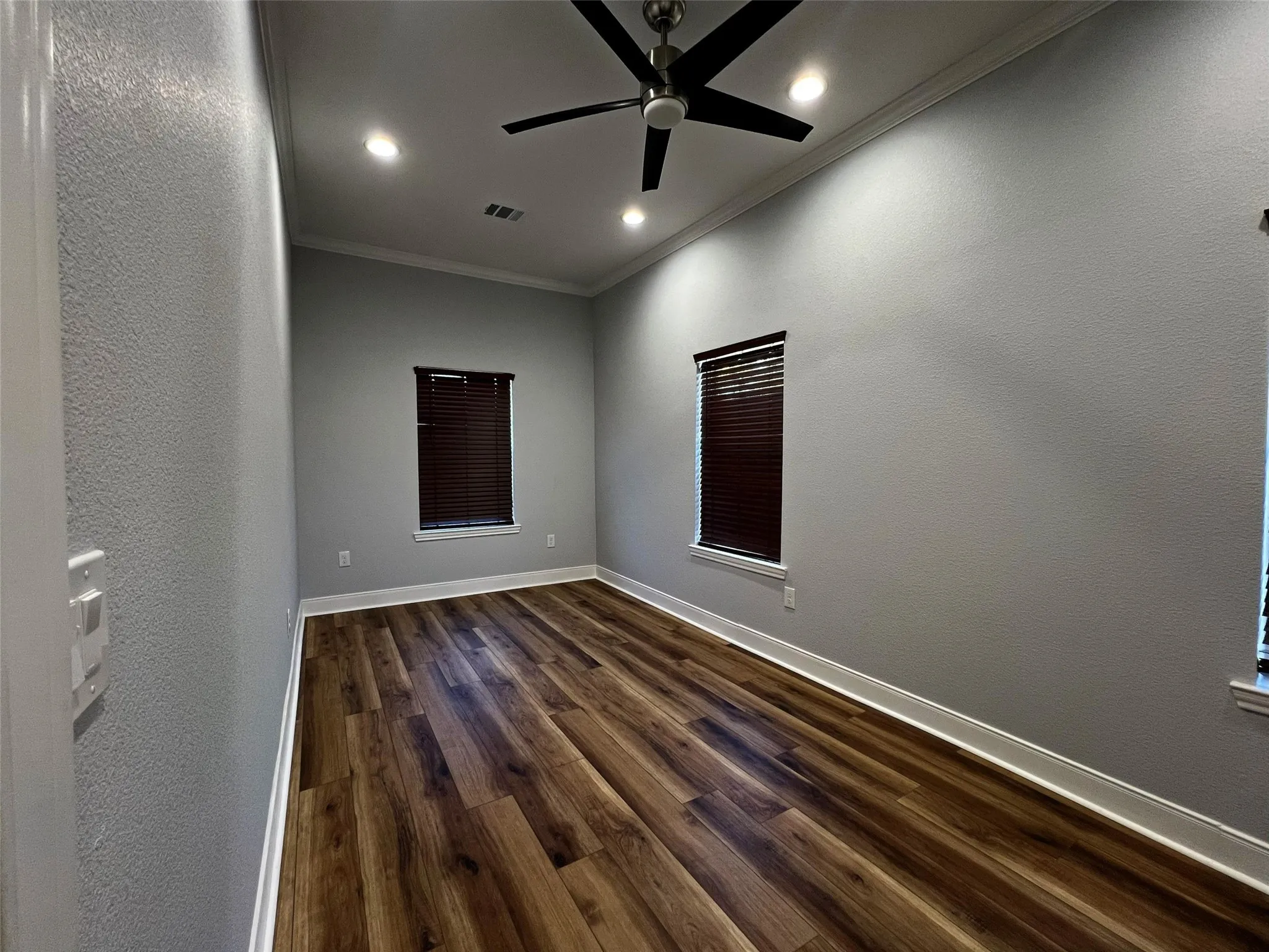 Spare room featuring dark wood finished floors, a textured wall, ornamental molding, recessed lighting, and a ceiling fan