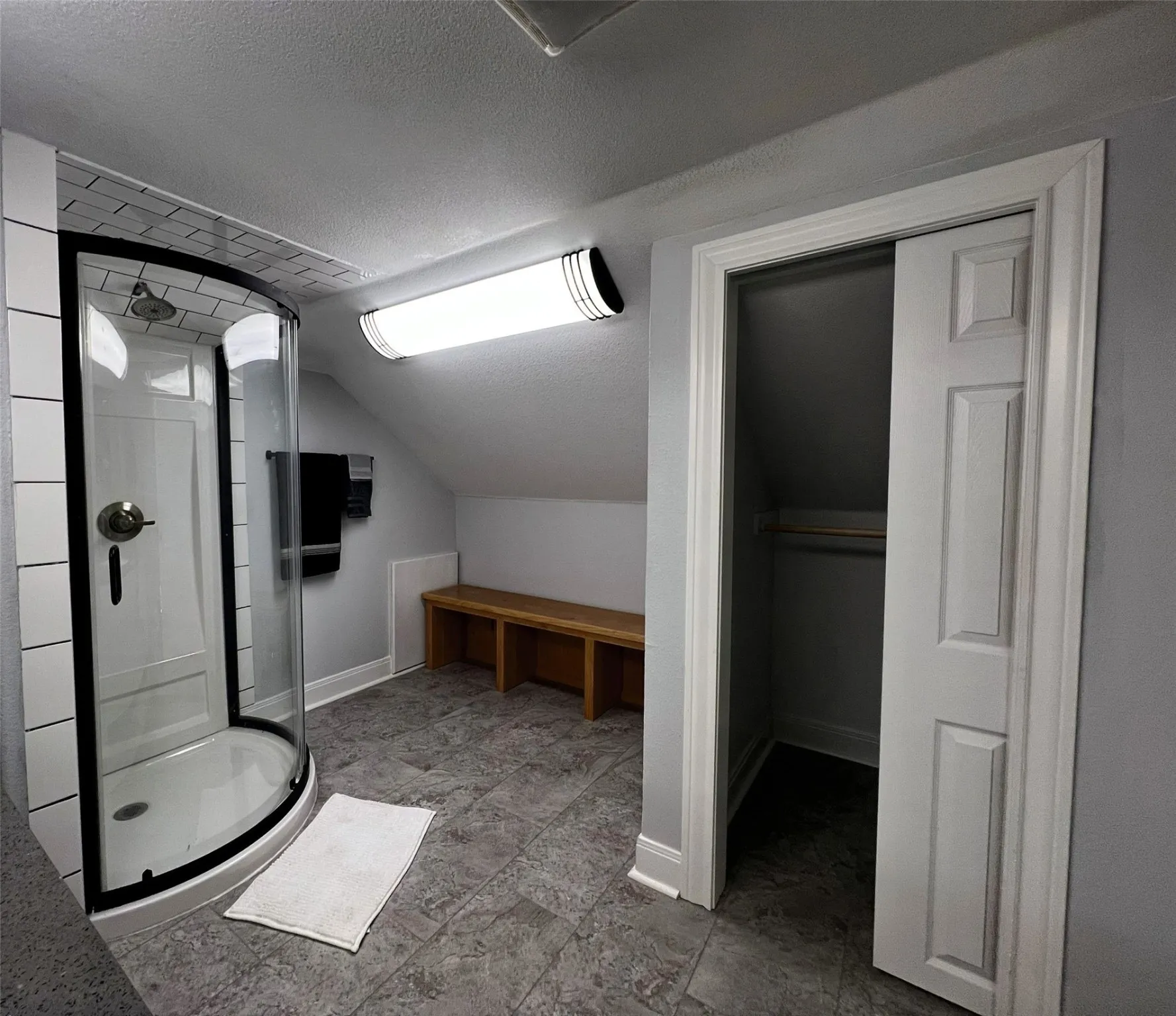 Bathroom with a textured ceiling, a shower stall, lofted ceiling, and a walk in closet