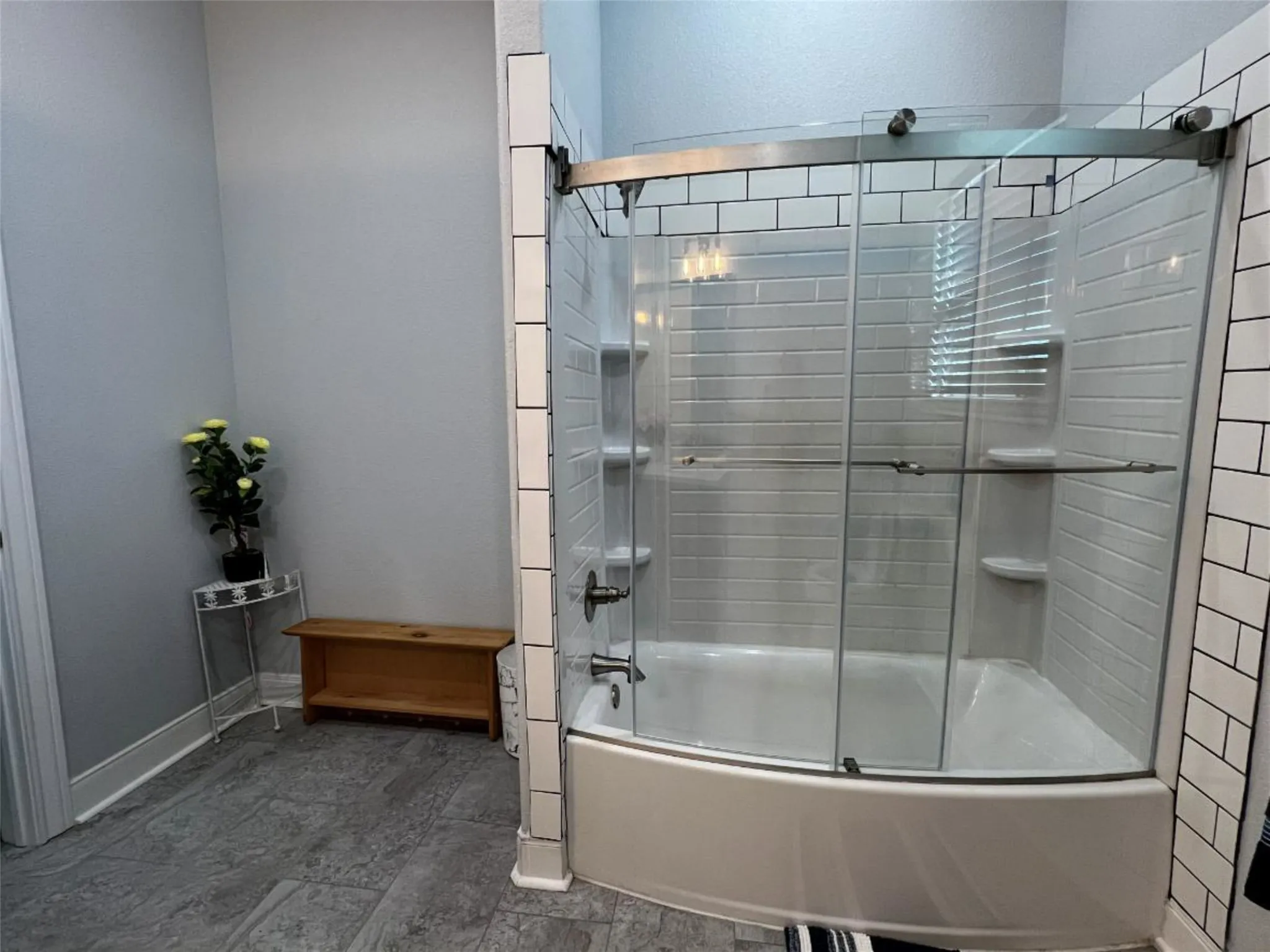 Full bath featuring combined bath / shower with glass door and baseboards