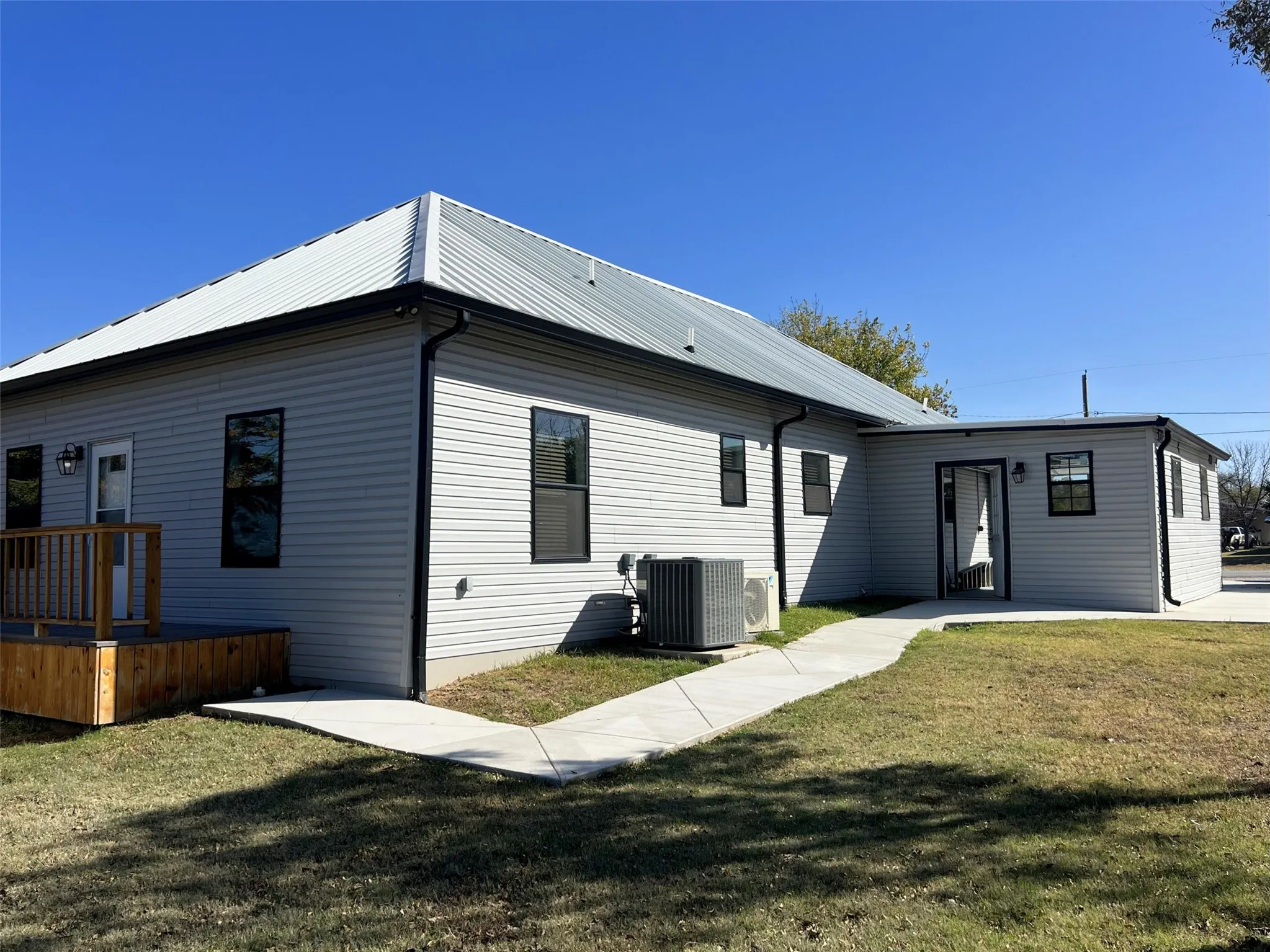 Back of property with a lawn and a metal roof
