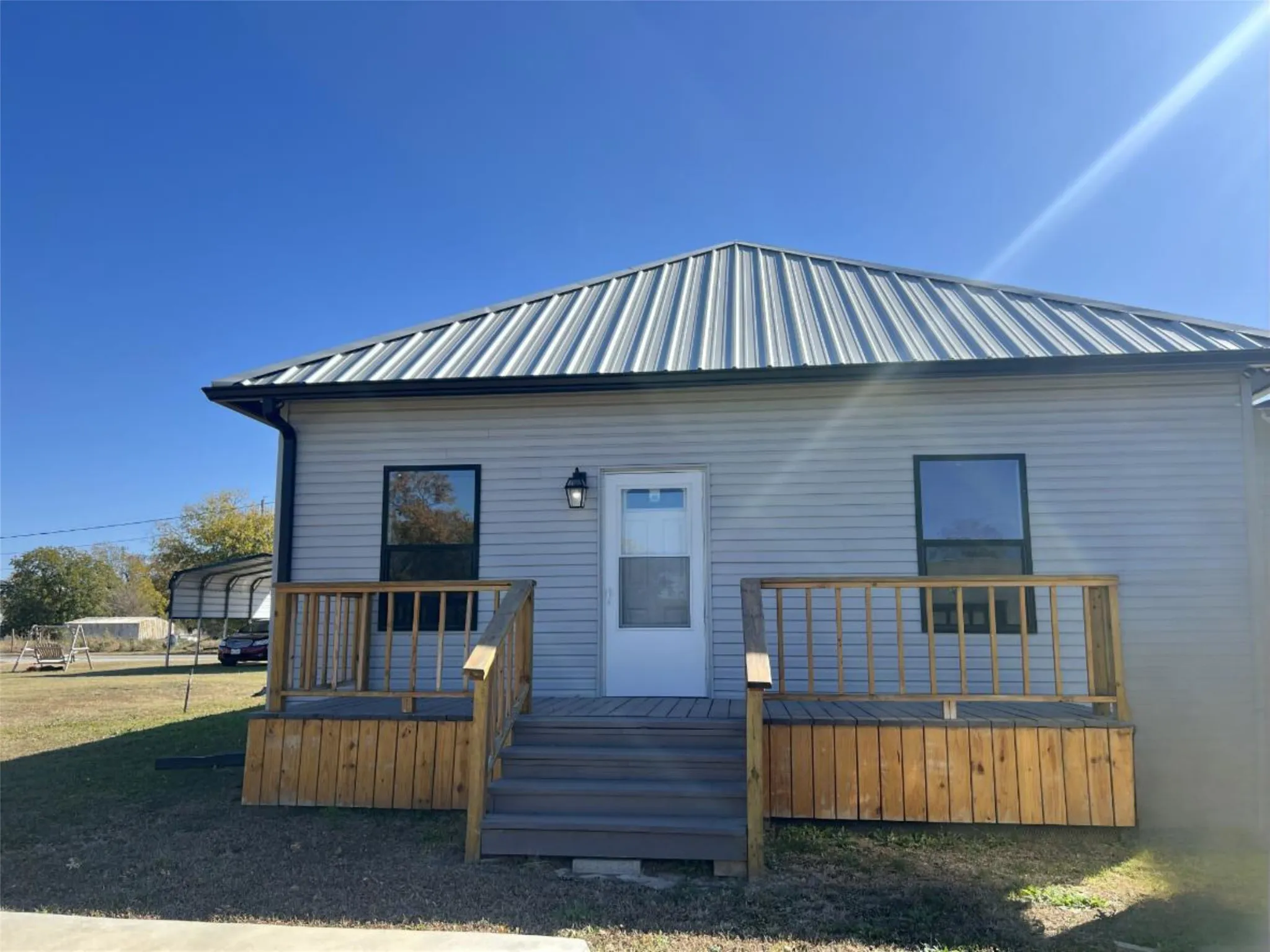 View of front of home featuring a wooden deck, a metal roof, and a carport