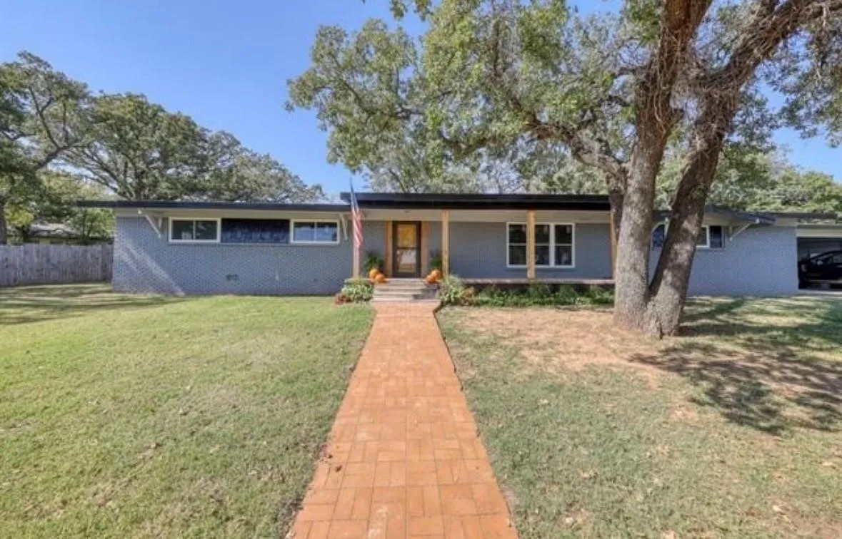 Ranch-style home featuring a porch and brick siding