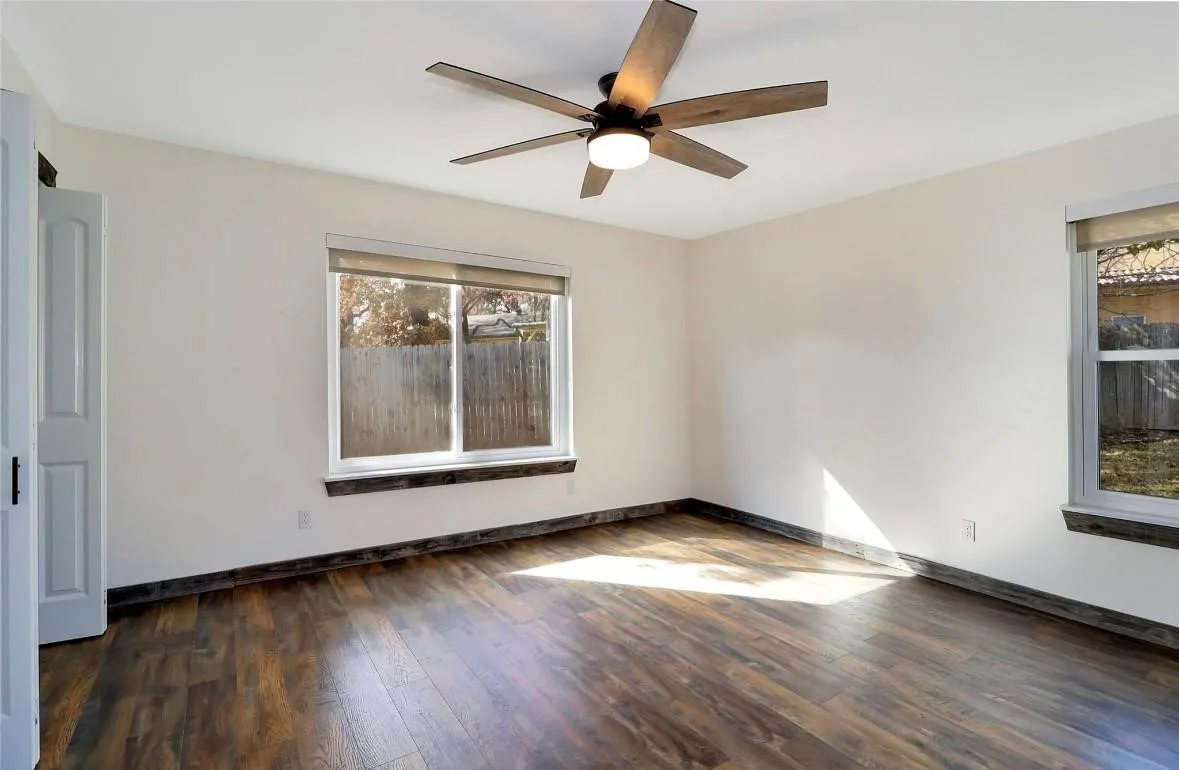 Empty room with dark wood-style floors and a ceiling fan