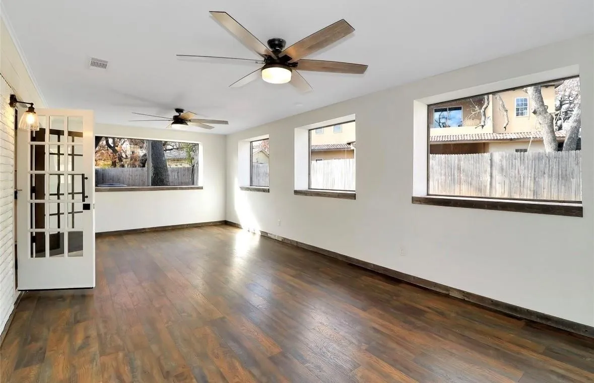 Empty room with dark wood finished floors and ceiling fan
