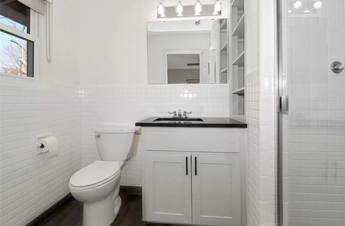 Bathroom featuring tile walls, vanity, a shower stall, dark wood-style floors, and a wainscoted wall