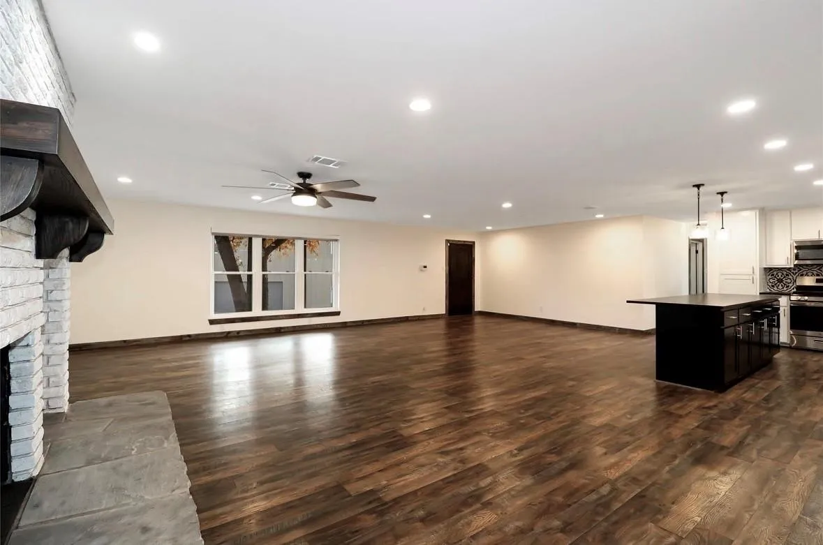 Unfurnished living room featuring dark wood-style flooring, a fireplace, ceiling fan, and recessed lighting