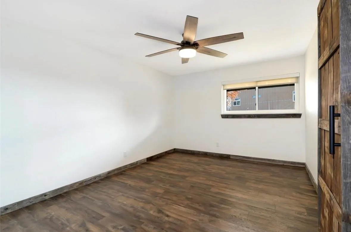 Spare room with dark wood-type flooring and a ceiling fan