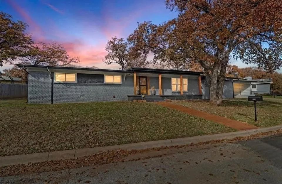 Single story home featuring a front lawn, brick siding, and a porch
