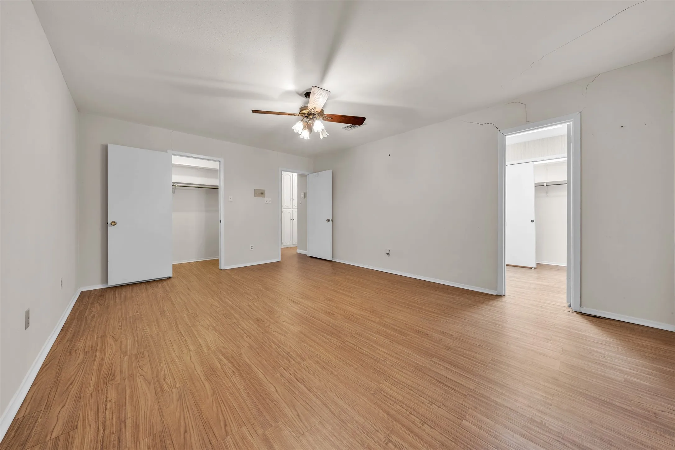 Unfurnished bedroom with light wood-style floors, a walk in closet, and a ceiling fan