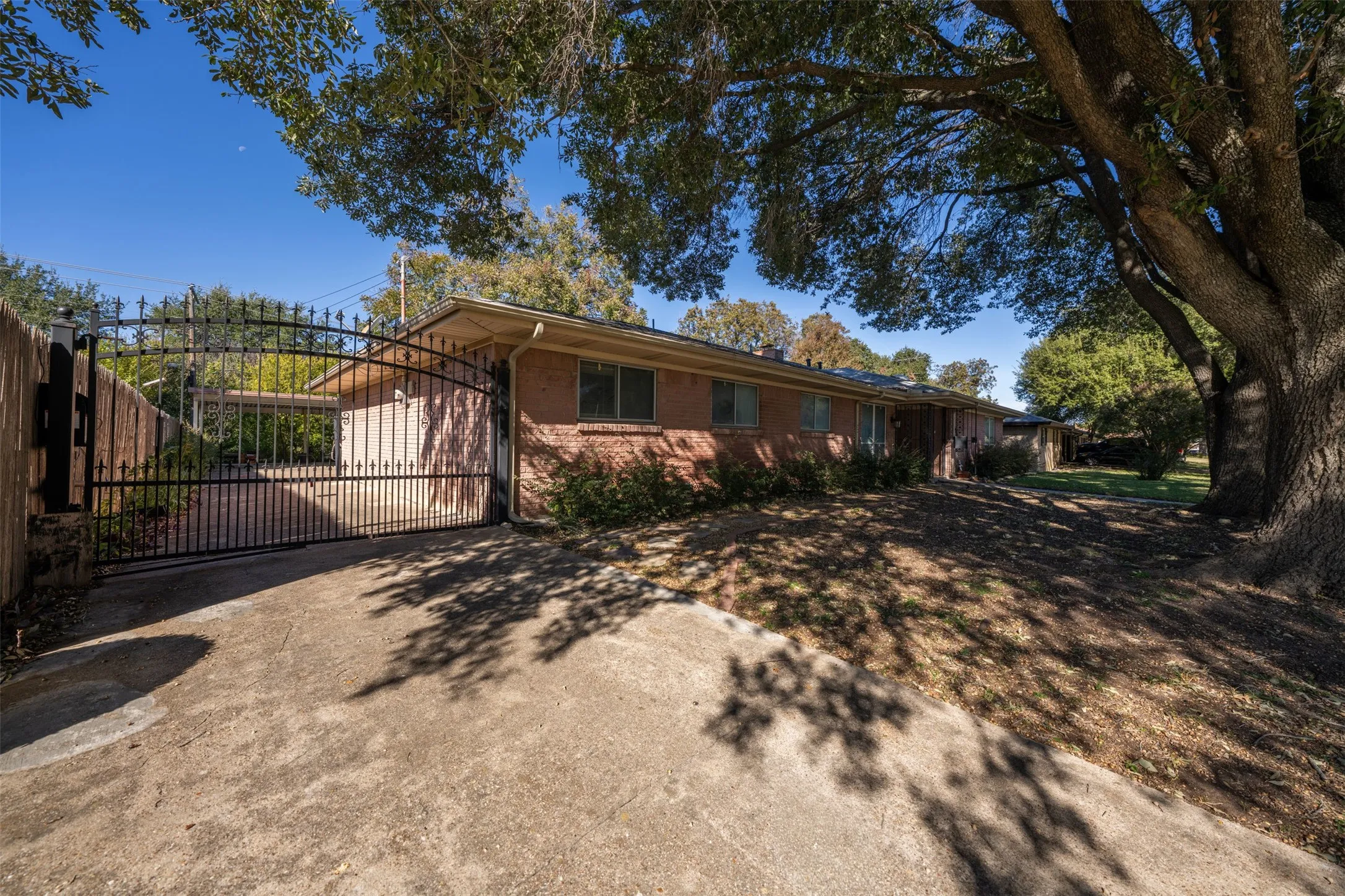 View of front of home featuring a gate, concrete driveway, and brick siding