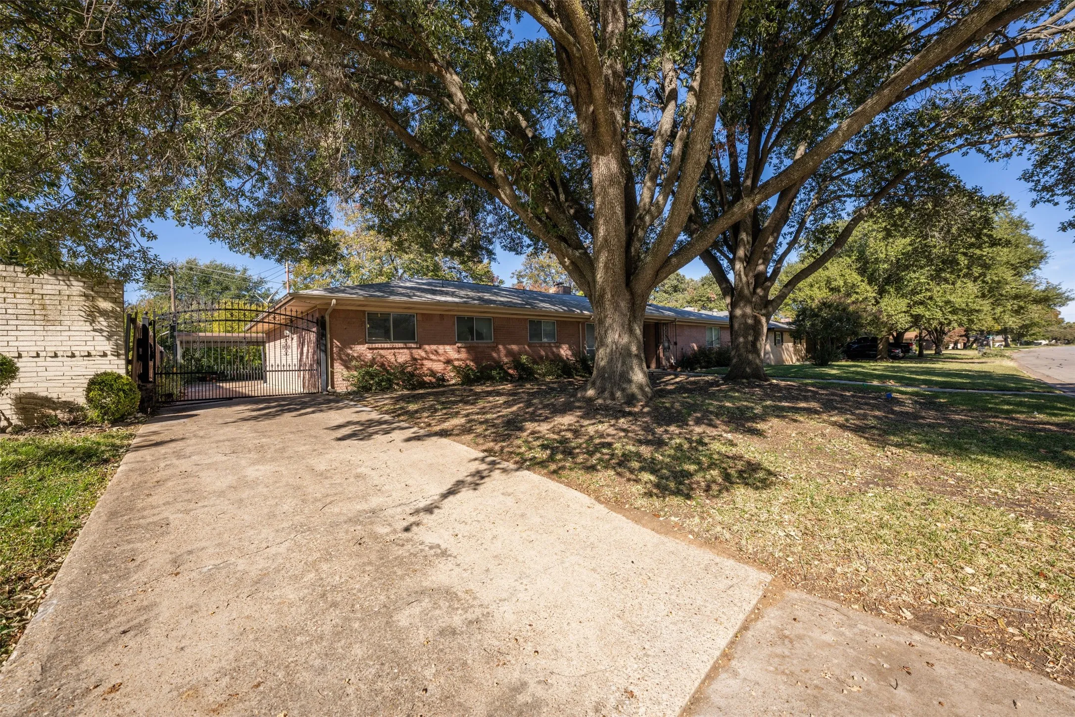Single story home featuring a gate, a front lawn, brick siding, and driveway