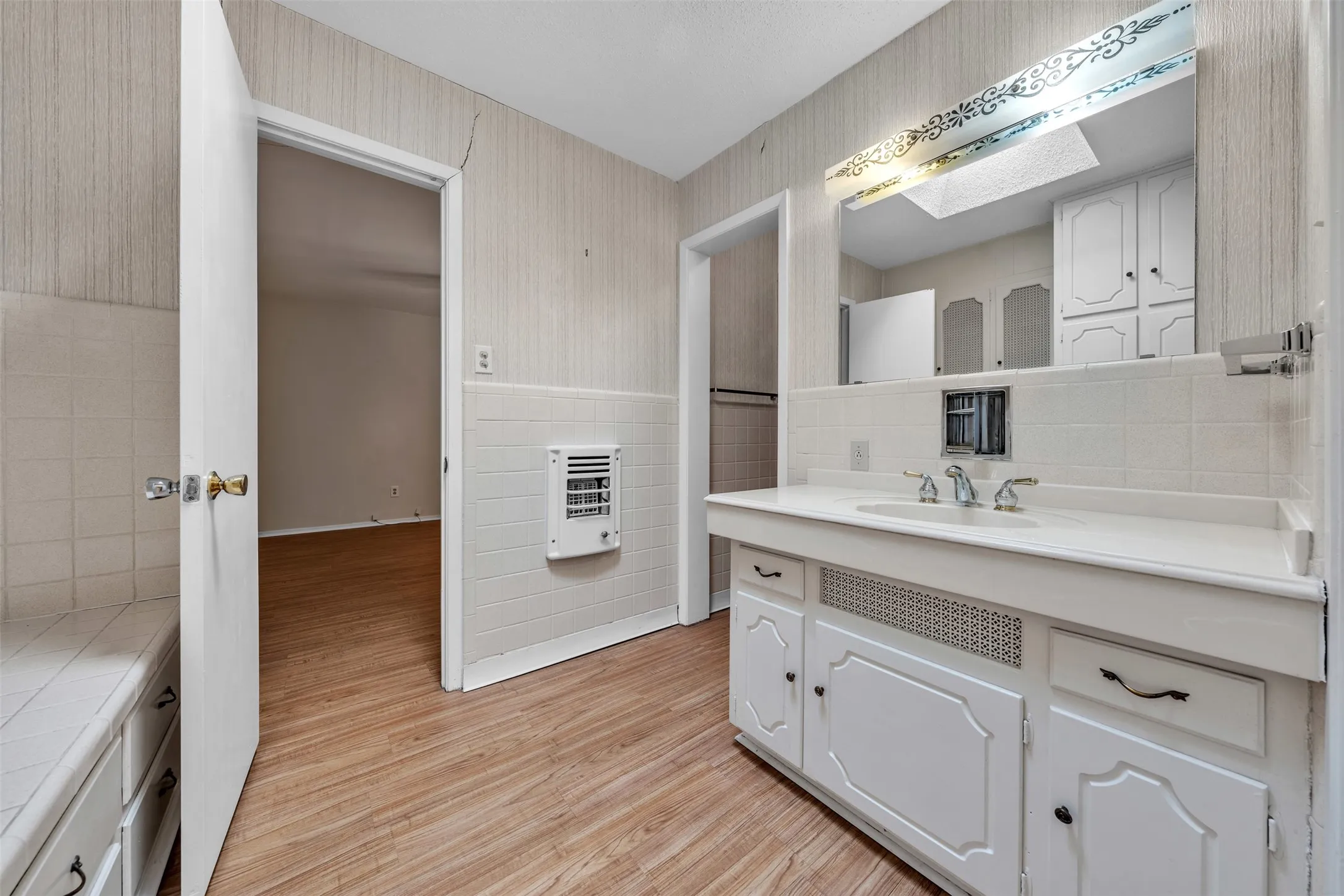 Bathroom featuring vanity, heating unit, tile walls, light wood-style flooring, and wallpapered walls