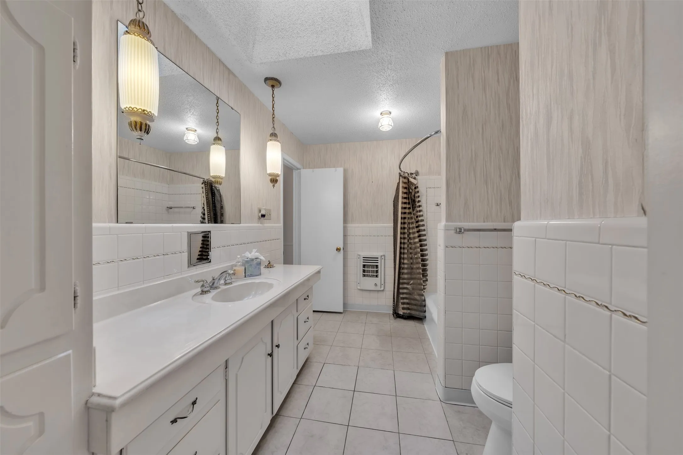 Full bathroom with vanity, a textured ceiling, light tile patterned flooring, tile walls, and heating unit
