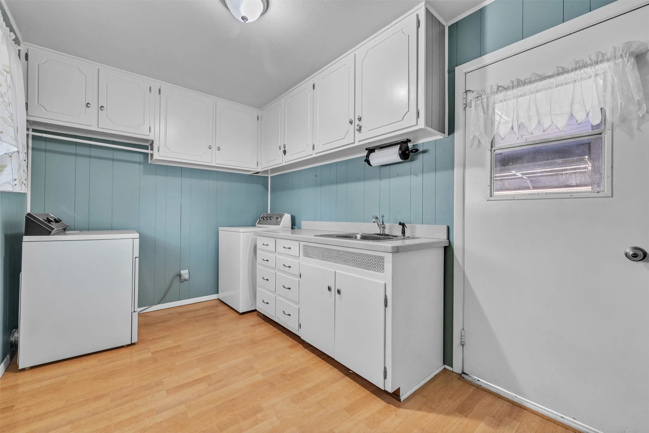 Washroom featuring light wood finished floors, wood walls, and cabinet space