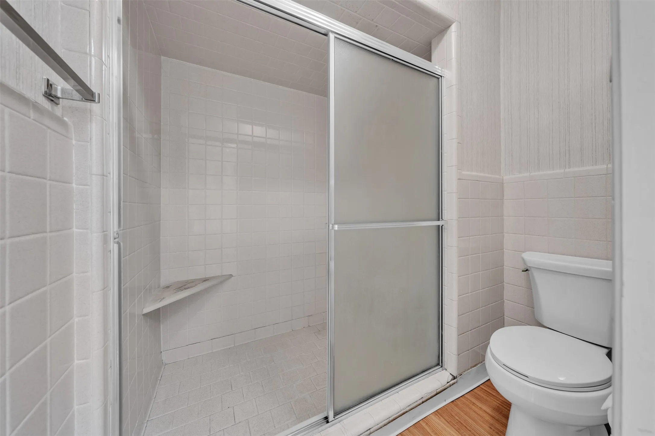 Full bath with a shower stall, tile walls, and wood finished floors