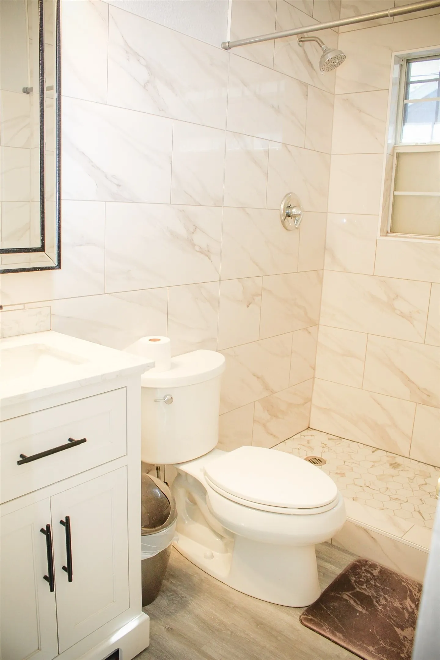 Bathroom with vanity, a shower stall, light wood finished floors, and tile walls
