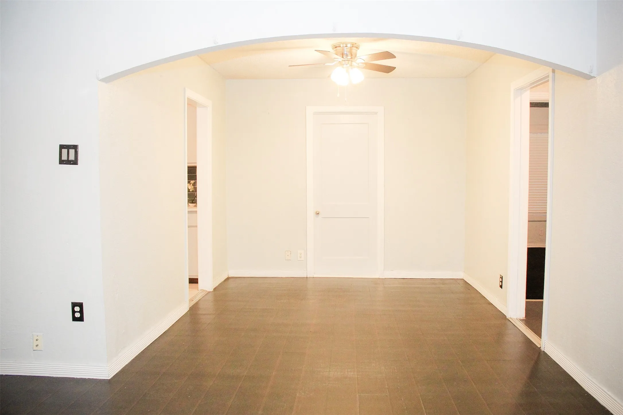 Empty room featuring arched walkways and ceiling fan