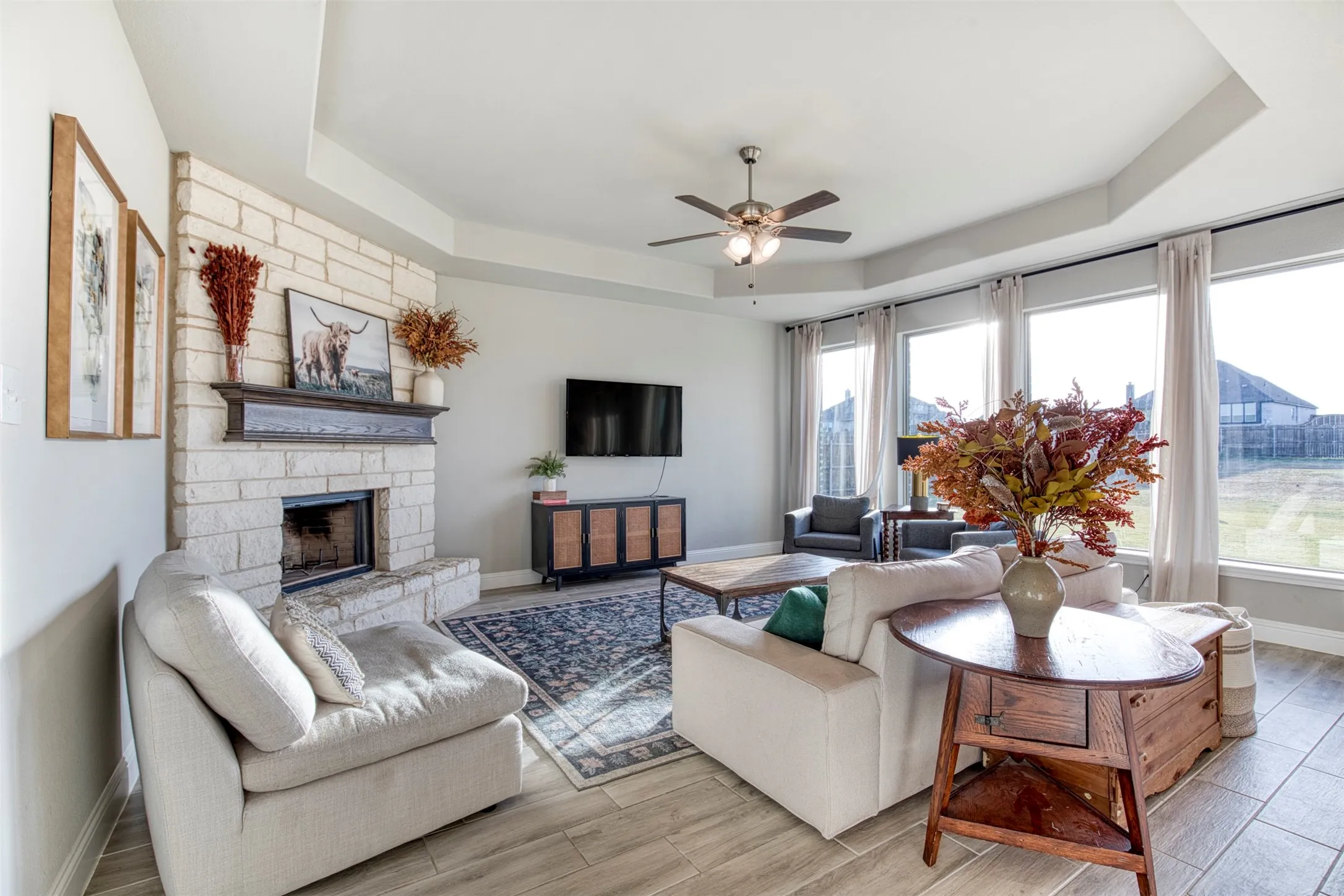 Impressive living room with tray ceiling and floor-to-ceiling stone fireplace with gas start.